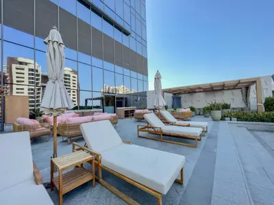 a row of lounge chairs and umbrellas on the roof of a building at Steps from Nakheel Mall and Monorail Station, Near Beach Clubs ,15 Mins to Downtown and Marina, The Palm Tower, Palm Jumeirah by Deluxe Holiday Homes in Dubai