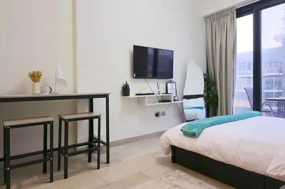 a bedroom with a bed and a desk and a tv at Azizi Riviera 43 - Meydan by Golden Casa in Dubai