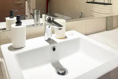 a white bathroom sink with two soap dispensers on it at Azizi Riviera 43 - Meydan by Golden Casa in Dubai