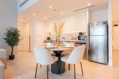 a kitchen with a table and chairs and a refrigerator at Steps from Marina Beach, AquaFun & The Walk, Mins to Bluewaters Island and Ain Dubai - La Vie, Jumeirah Beach Residence by Deluxe Holiday Homes in Dubai