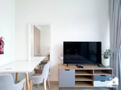 a living room with a television on a wooden entertainment center at Amazing Studio in Meydan l Pool , Gym & Balcony in Dubai