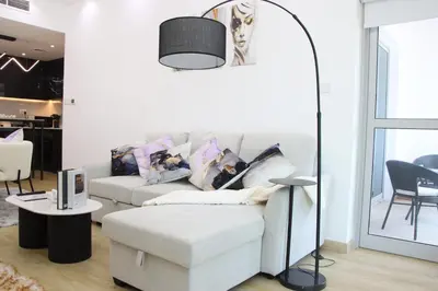 a living room with a white couch and a table at Dubai Marina 1BR with Balcony, Near Metro, Walk to JBR beach & Marina Promenade in Dubai
