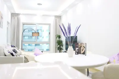 a white living room with a table and a couch at Dubai Marina 1BR with Balcony, Near Metro, Walk to JBR beach & Marina Promenade in Dubai