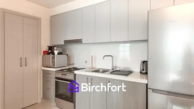 a kitchen with white cabinets and a stainless steel refrigerator at Elegant Flat in Prime Location in Dubai