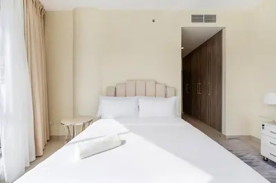 a bedroom with a large white bed with a wooden door at FAM Living - 2BR Apartment with Burj & Canal Views at The Bay in Dubai