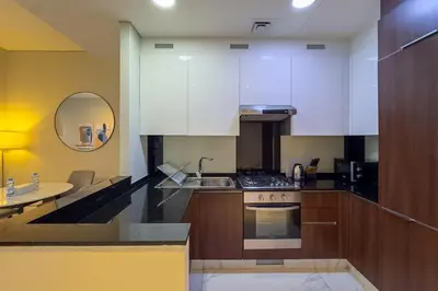 a kitchen with white cabinets and a sink and a table at Stylish 1B in J one With Balcony & Canal View in Dubai