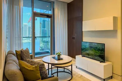 a living room with a couch and a tv and a table at 1BR City Escape l Canal & Skyline Views in Dubai