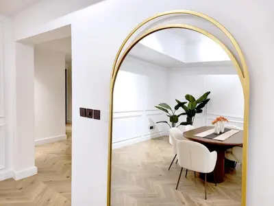 a dining room with a round table and a gold mirror at SOLARTE Luxe - New Large 2BR - Marina Promenade - Sea Views - Super King Bed & Workspace in Dubai