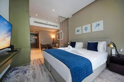 a hotel room with a large bed and a flat screen tv at Cozy Studio in Damac Prive - Free Gym & Pool in Dubai