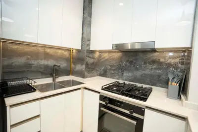 a kitchen with white cabinets and a sink and a stove at Spacious Luxe 2BR in Dubai - With Pool and Gym in Dubai