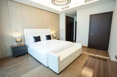 a large white bed with a white couch in a bedroom at Spacious Luxe 2BR in Dubai - With Pool and Gym in Dubai