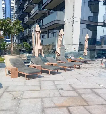 a row of lounge chairs and umbrellas in front of a building at Spacious Luxe 2BR in Dubai - With Pool and Gym in Dubai