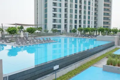 a large swimming pool with chairs and a building at Luxury2BR BurjKhalifa View Infinity Pool Mall Walk in Dubai