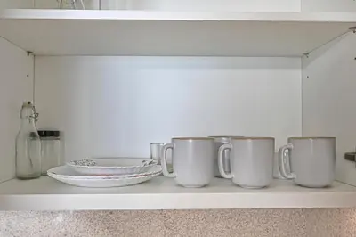 a shelf with four coffee cups and plates on it at Golden Stays - Sky High 2BR I Burj Khalifa Views & Mallside Charm I Dowtown Dubai in Dubai