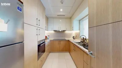 a kitchen with wooden cabinets and a stainless steel refrigerator at bnbmehomes - Vida Residence A1 in Dubai