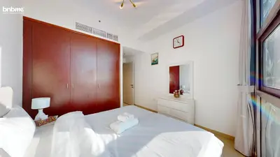 a bedroom with a large white bed with a wooden headboard at bnbmehomes - DEC Tower 1 in Dubai