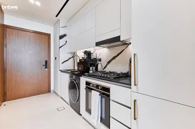 a kitchen with white cabinets and a stove top oven at bnbmehomes - Trillionaire Residences By Binghatti in Dubai