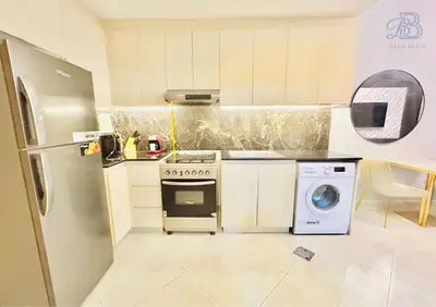 a kitchen with a stove and a washing machine at 1 Bedroom Apartment in Al Jaddaf - High-Floor with Dubai Skyline View in Dubai