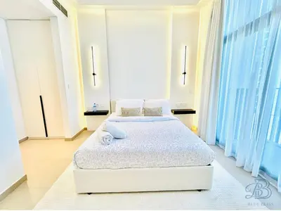 a white bedroom with two beds and large windows at Stylish 2 Bedroom Apartment in the Heart of JVC - with swimming pool, fully equipped gym, outdoor steam room, kids play area & lots more in Dubai