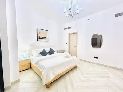 a white bedroom with a bed and a tv at Stylish 1 Bedroom Apartment in the Heart of JVC in Dubai