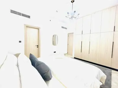 a white bedroom with two beds and a window at Stylish 1 Bedroom Apartment in the Heart of JVC in Dubai