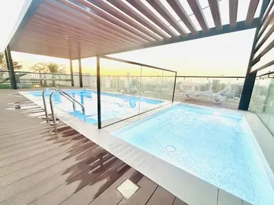 a large swimming pool with a view of a building at Stylish 1 Bedroom Apartment in the Heart of JVC in Dubai