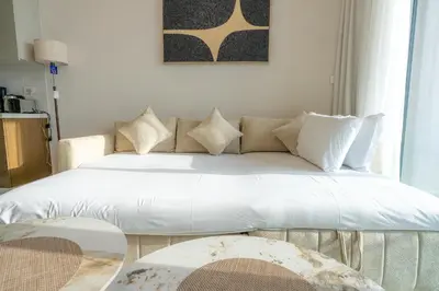 two beds in a living room with a couch at Elegant Downtown Escape 1BR w Balcony, Pool & Gym in Dubai