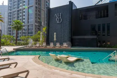 a swimming pool with two lounge chairs in front of a building at Urban Studio - Business Bay in Dubai