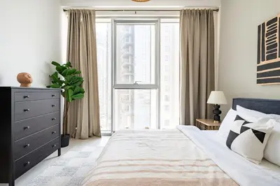 a bedroom with a bed and a dresser and a window at The Grand Luxury Residential I1Bedroom I High Floor I Water View I Tennis & Badminton Courts I Rooftop Lounge in Dubai