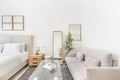 a white living room with a couch and a table at Bright Modern Studio in the Heart of JVC in Dubai