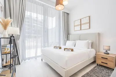 a white bedroom with a bed and a window at Bright Modern Studio in the Heart of JVC in Dubai