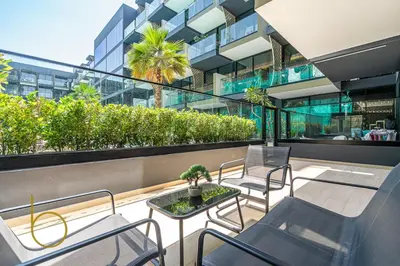 a balcony with chairs and a table and a building at Bookable - 1 Bedroom Binghatti Crescent in Dubai