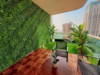 a balcony with a green wall with a chair and plants at Luxury Studio Apartment with large Balcony and Sea Views, free Parking, Dubai Marina - JBR in Dubai