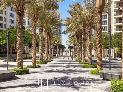 a row of palm trees in a park with buildings at LUX The Dubai Creek Beach Suite 2 in Dubai