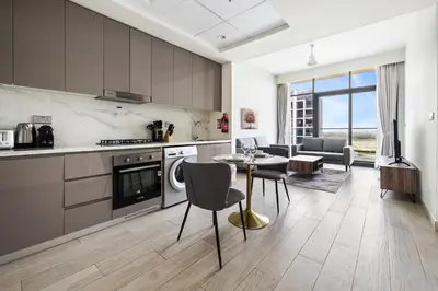 a kitchen and living room with a table and chairs at 1BR Azizi Riviera 44 City Skyline View in Dubai