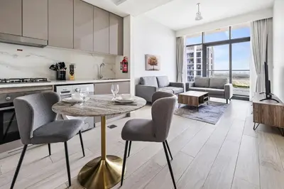 a kitchen and living room with a table and chairs at 1BR Azizi Riviera 44 City Skyline View in Dubai