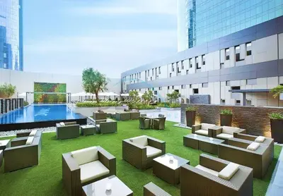 a hotel patio with couches and a pool at City View Studio on High Floor, Steps from Metro, Beside Water Canal, Quick Downtown Access, The Cosmopolitan, Business Bay by Deluxe Holiday Homes in Dubai