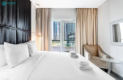 a hotel room with a large white bed and a chair at Blue Breeze - Stunning 1BR with Canal & Pool Views in Dubai