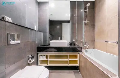 a bathroom with a sink and a toilet and a tub at Blue Breeze - Stunning 1BR with Canal & Pool Views in Dubai