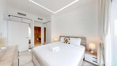 a white bedroom with a white bed and a mirror at Marina Gate 2 - High Rise One Bed with Marina View in Dubai
