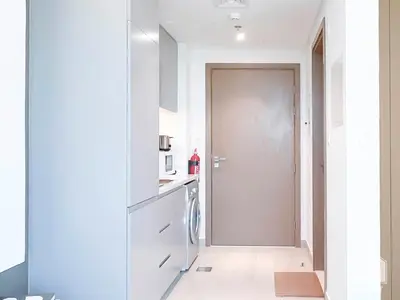 a white kitchen with a washer and dryer at Breathtaking Studio with Balcony & Stunning Views in Dubai