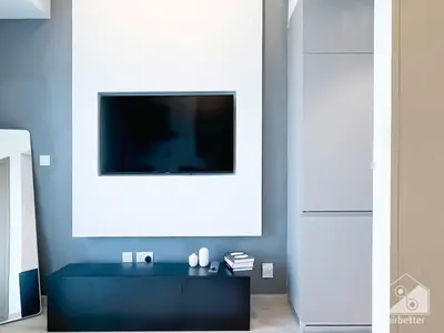 a living room with a tv on a blue wall at Breathtaking Studio with Balcony & Stunning Views in Dubai