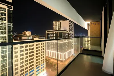 a balcony with a view of a city at night at 2BR Luxury Baby, Gym & Pool in Dubai