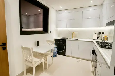 a white kitchen with a small table and a sink at 2BR Luxury Baby, Gym & Pool in Dubai