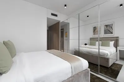 a white bedroom with two beds and a mirror at Maison Privee - Sky-High Panoramic Apt with Iconic Burj Khalifa Vws in Dubai