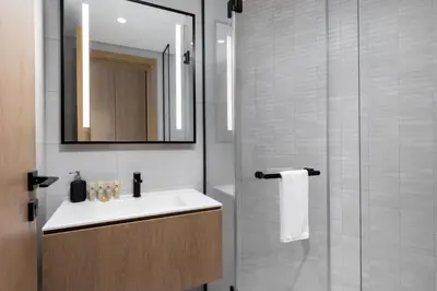 a bathroom with a sink and a mirror and a shower at Maison Privee - Sky-High Panoramic Apt with Iconic Burj Khalifa Vws in Dubai