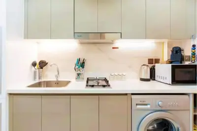 a white kitchen with a sink and a dishwasher at Guest Favorite - Relaxed and Cozy Studio Near Racecourse in Dubai