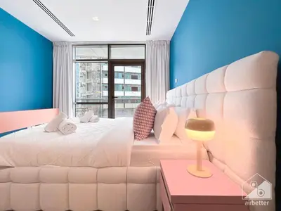 a bedroom with a white bed and a window at Colorful Studio with Balcony & City Views in Dubai