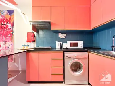 a kitchen with red cabinets and a washing machine at Colorful Studio with Balcony & City Views in Dubai
