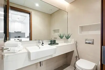 a bathroom with a sink and a toilet and a mirror at Stunning 1BR Canal Front Residence near Downtown in Dubai